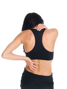 Isolated studio shot of a woman in a fitness outfit experiencing neck, shoulder  and back pain.